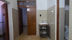 A narrow hallway with a wooden door at the end, a small sink with a mirror, and a toilet visible through an open door. - 2 bedroom apartment near parque dela plancha park merida yucatan (Mérida)
