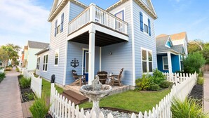 A two-story house with a balcony, a front porch, and a small garden with a birdbath. - Waterfront Community with Private Pier + Pool (Rockport)