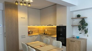Eine moderne Küche mit Essbereich, ausgestattet mit hellem Holzkorpus, einer zentralen Kochinsel und integrierten Geräten.
