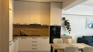 Eine moderne Küche mit weißen Schränken, einer Holzauskładung und einem Essbereich mit Tisch und Stühlen.