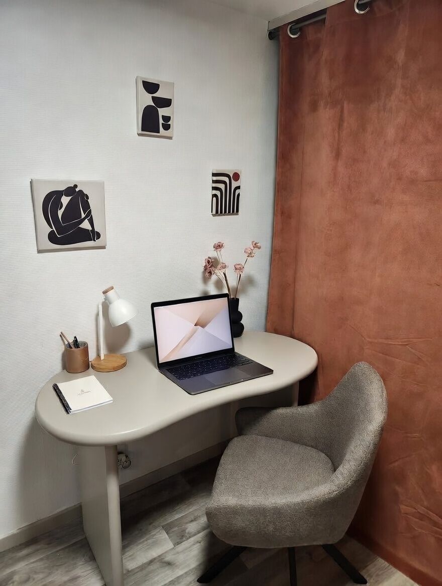 Un'area di lavoro moderna con un laptop, una scrivania, una sedia e decorazioni murali.