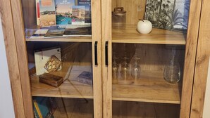 Un meuble en bois doté de portes en verre, contenant des livres, un petit vase blanc et un objet décoratif sur lequel figure le mot « HOME » sur la porte de droite.