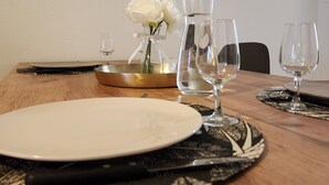 Una mesa de comedor dispuesta con platos, vasos y un jarrón con flores.