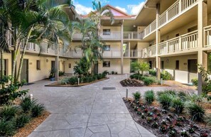 A courtyard with a central paved area, surrounded by multi-story buildings with balconies. - NEW on VRBO! Exclusive Bonita Bay Resort style living. 2 Bed, 2 Bath condo. (Bonita Springs)