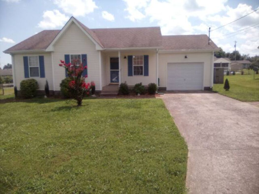 A single-story house with a front garage, a small porch, and a well-maintained lawn.