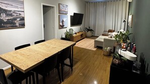 A modern living room with a wooden dining table, black chairs, a sofa, and a TV mounted on the wall. - Leblon Penthouse: Everything within walking distance! (Rio de Janeiro)
