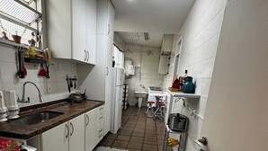 A compact kitchen with white cabinets, a tiled floor, and a striped rug. - Leblon Penthouse: Everything within walking distance! (Rio de Janeiro)