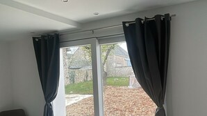 Il s’agit d’une chambre moderne dotée d’une grande porte-fenêtre coulissante qui donne sur un patio. La chambre contient une chaise et une petite table.