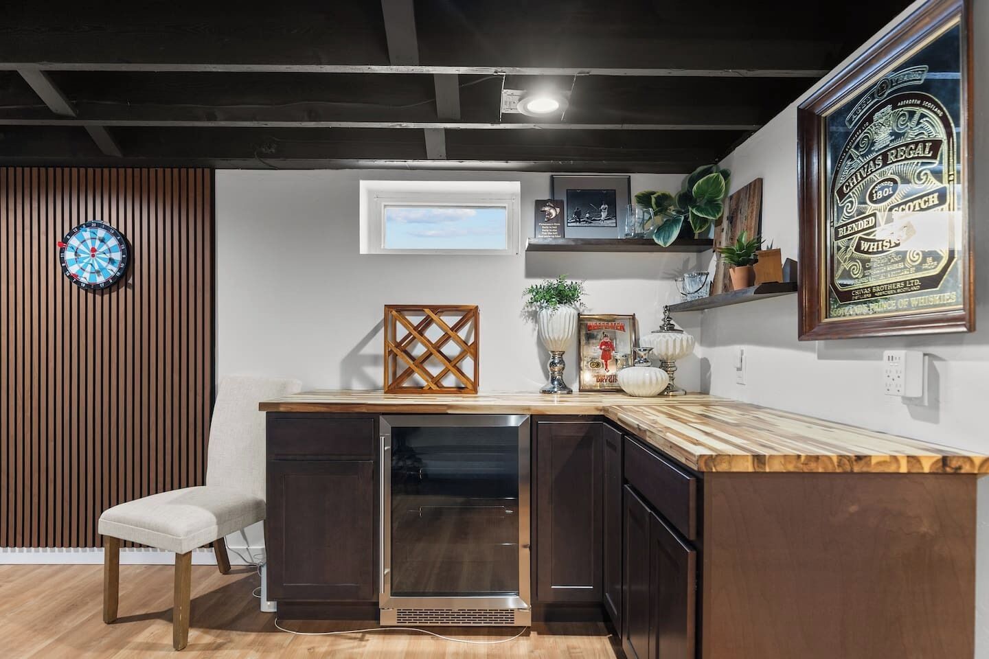 Een moderne keuken met een houten aanrechtblad, een ingebouwde oven en een dartbord aan de muur.