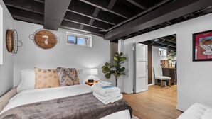 Une chambre à coucher moderne avec un lit, une table de chevet avec une lampe, une horloge et une fenêtre.