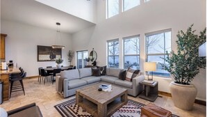 Een ruime woonkamer met een grote hoekbank, een salontafel en een eethoek met een tafel en stoelen.