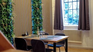 A dining area with a wooden table, black chairs, and a window with curtains.