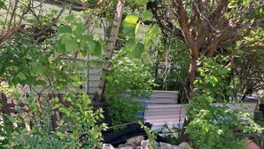 A garden area with a pile of rocks, a green tarp, and a tree.