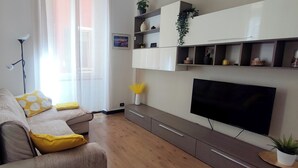 A living room with a sofa, TV, and built-in shelves. - Porta Soprana House, in heart of historic center, bright and close to everything (Genova)