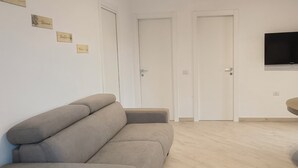 Ett rum med en soffa, ett matbord och en tv som är monterad på väggen.