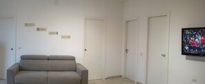A room with a sofa, a television, and a wall with four nameplates.