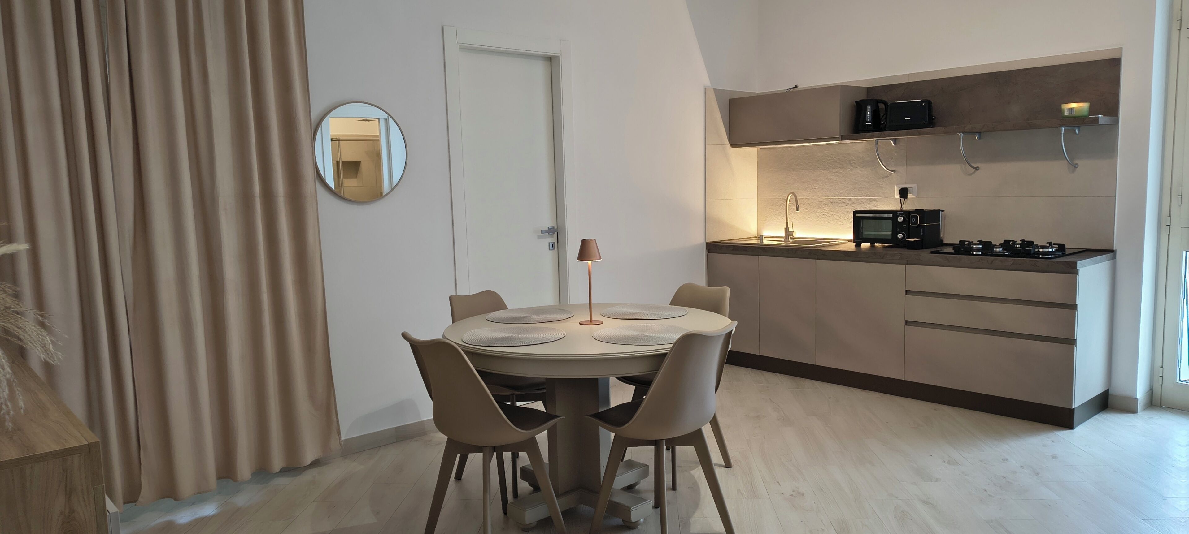 Una cucina moderna con piano cottura integrato, una piccola isola con lavello e un'area pranzo con tavolo e sedie rotonde.
