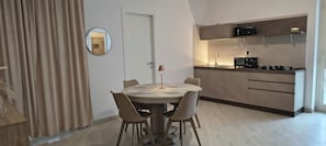 A modern kitchen with a built-in stove, a small island with a sink, and a dining area with a round table and chairs.