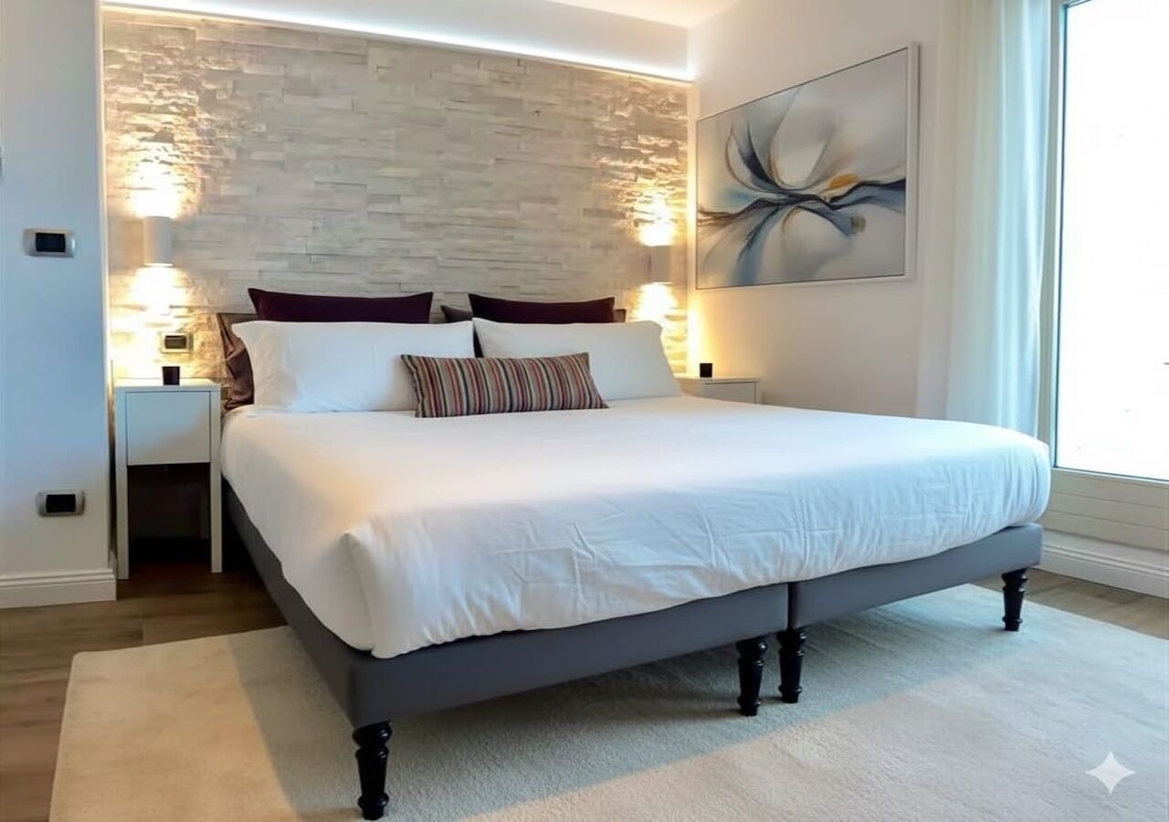 A modern bedroom with a large bed, a stone accent wall, and a painting.