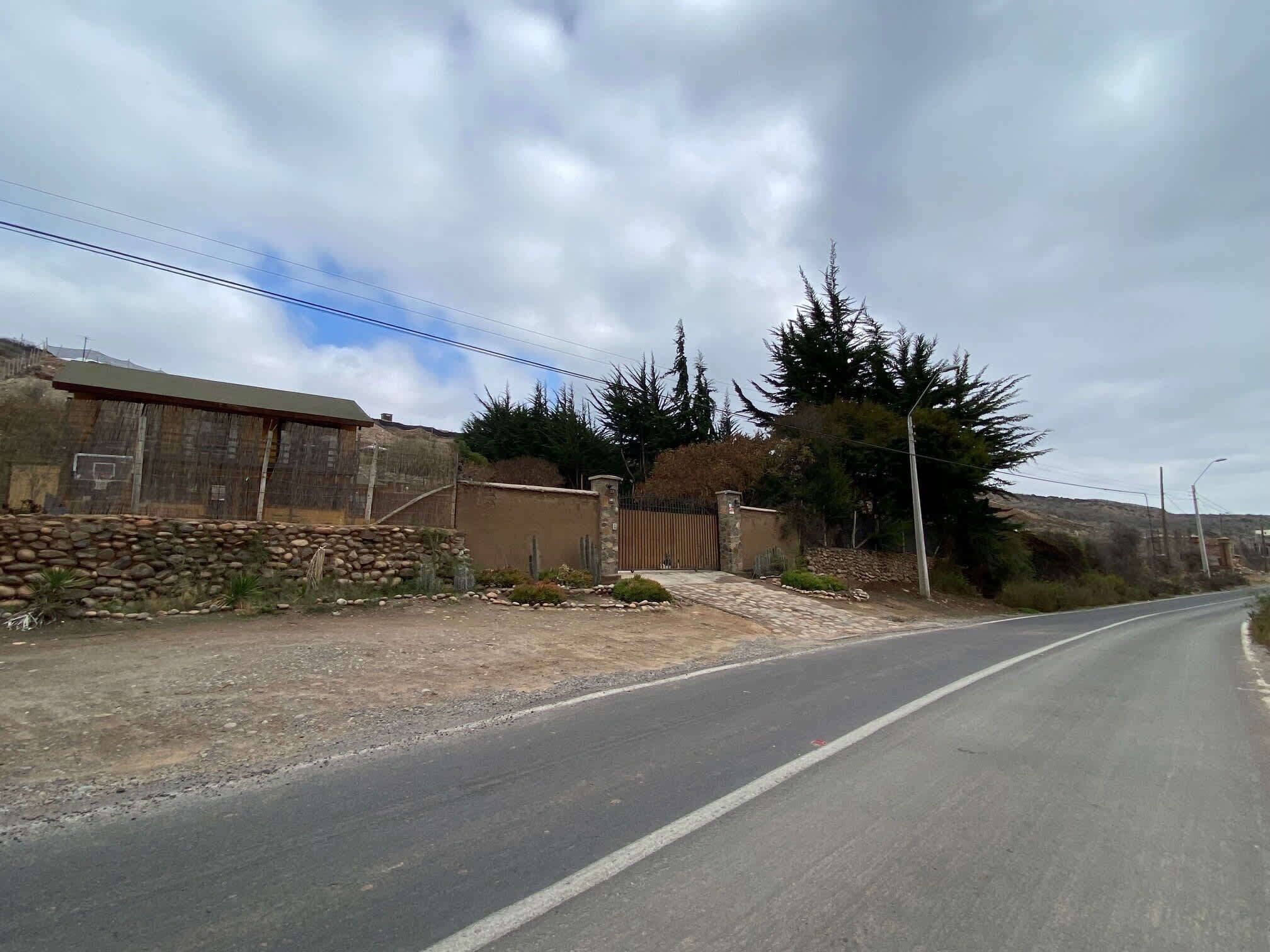 Eine ländliche Straße mit einer Steinmauer und einem Holzhaus links.