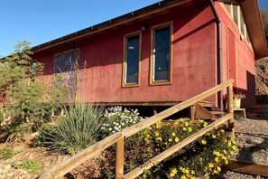 A red building with two windows and a wooden staircase leading up to a door. - Scenic Mountain-View Cabin w/ Pool & BBQ Terrace (La Serena)