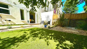 Ein gepflegter Garten mit Rasen, Kübelpflanzen und einem Holzzaun.