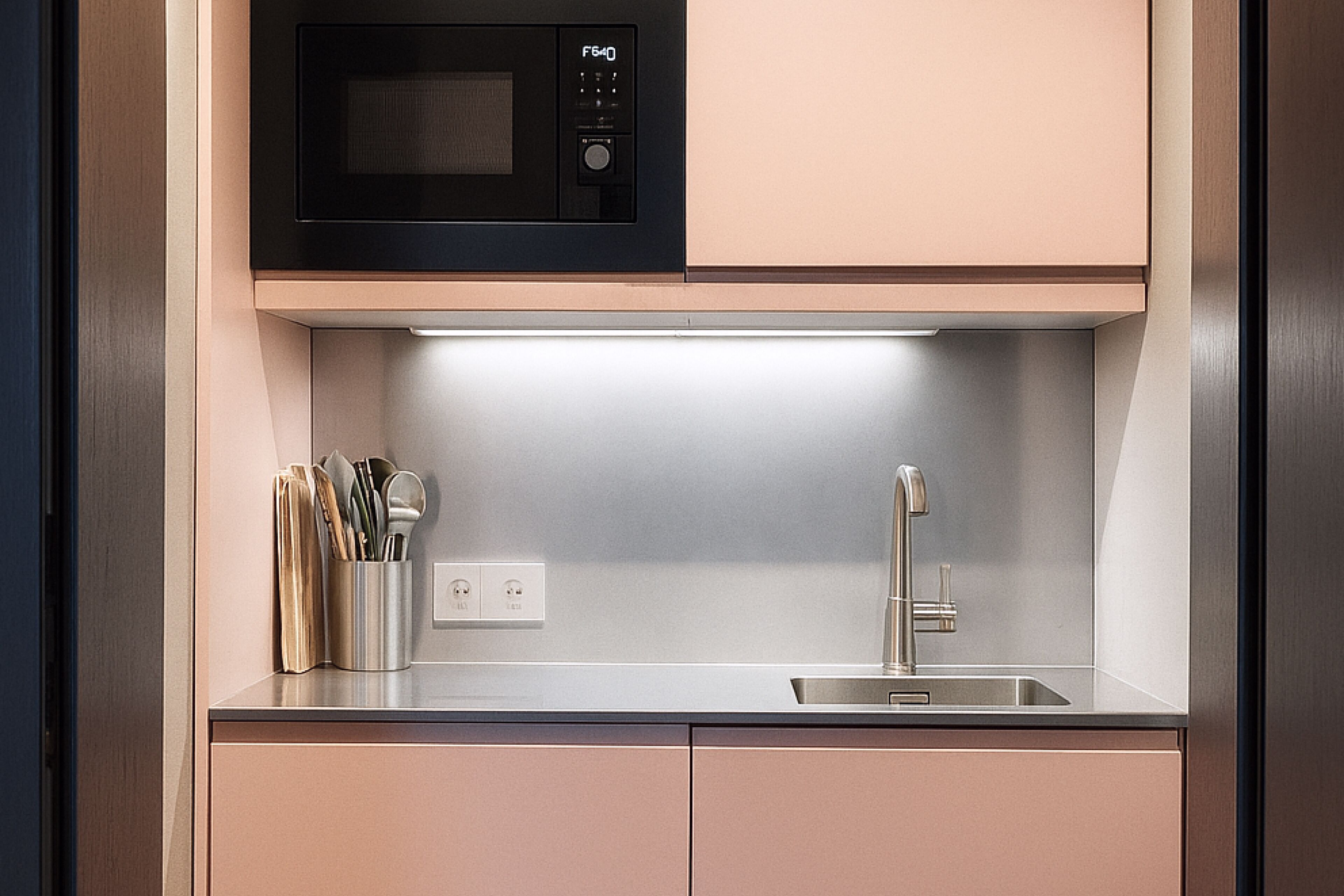 A modern kitchen with a built-in microwave, a stainless steel sink, and a knife block.