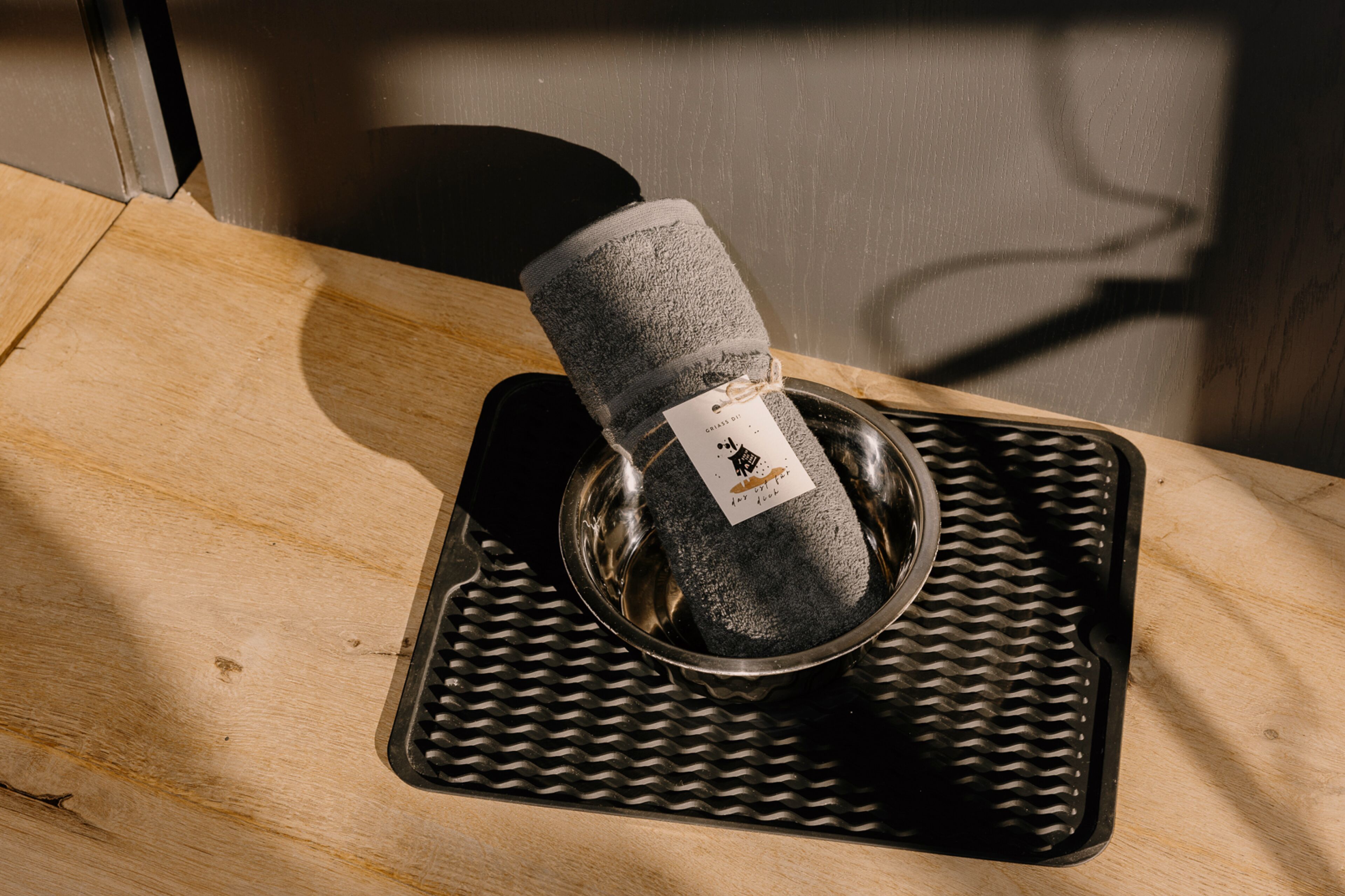 A metal bowl with a cloth inside, placed on a textured mat.