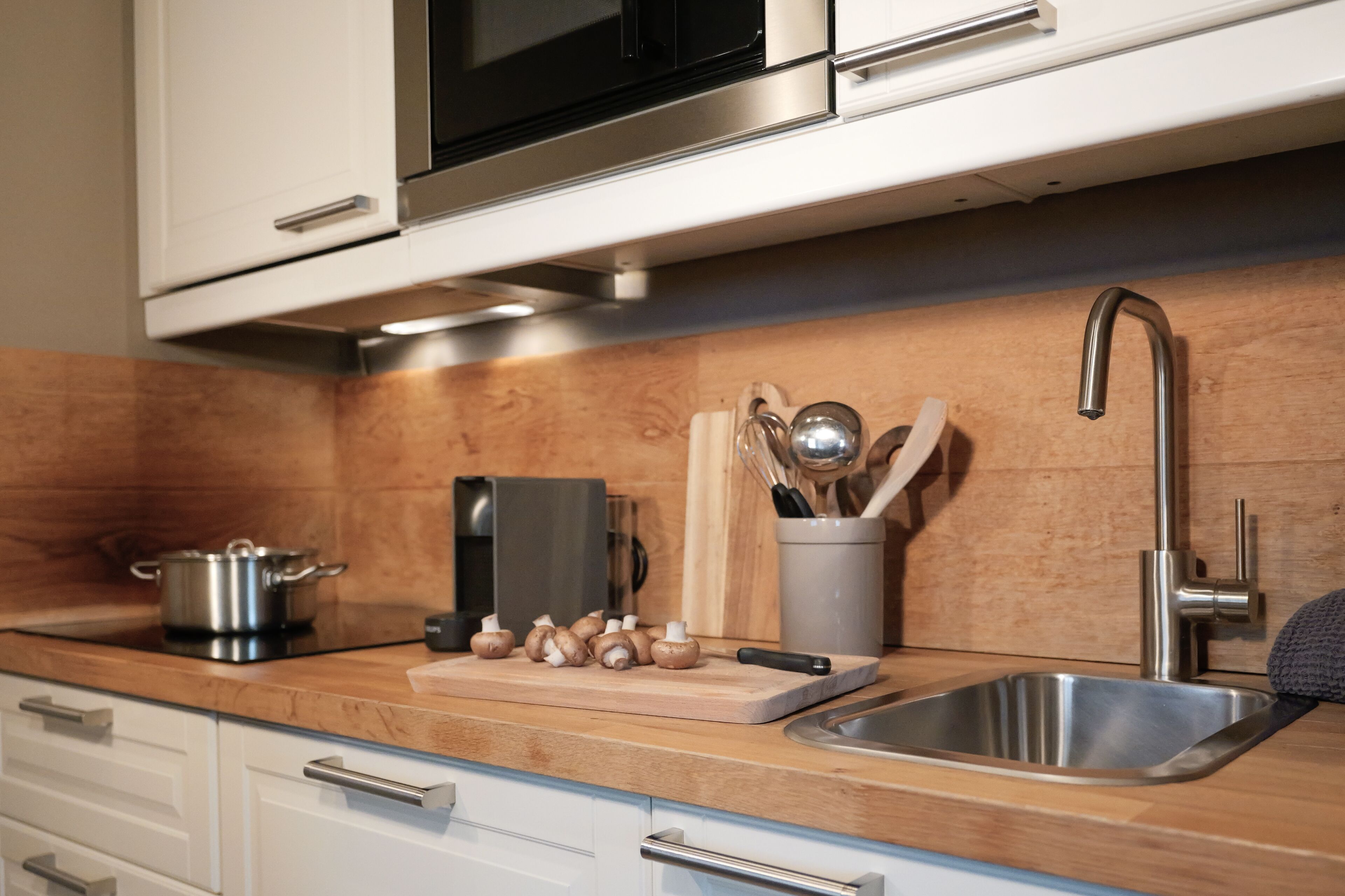 Una cocina moderna con electrodomésticos de acero inoxidable, encimeras de madera y un lavamanos integrado.