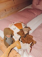 A bed with a checkered bedspread and pillows, and several plush toys on the bed.