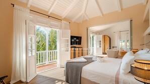 Una camera da letto con un letto grande, un balcone e vista su palme.
