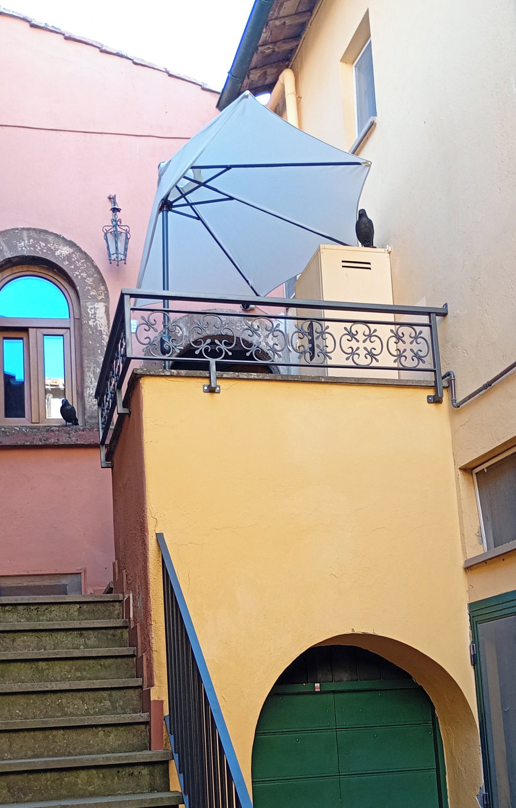 Ein Gebäude mit einer gelben Fassade, einer grünen Tür und einem blauen Vordach.