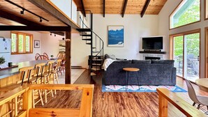 A modern interior with a wooden ceiling, a staircase, a dining area, and a living room with a sofa and TV. - Bluebird Chalet - Spacious 3 bedroom + loft.  Storyland, North Conway, Jackson (Bartlett)