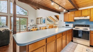 A kitchen with wooden cabinets, a large island, a stove, and a dining area with chairs and a table. - Bluebird Chalet - Spacious 3 bedroom + loft.  Storyland, North Conway, Jackson (Bartlett)