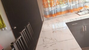 Eine Küche mit Marmorarbeitsplatte, Spüle und einem Fenster mit orangenen Vorhängen.