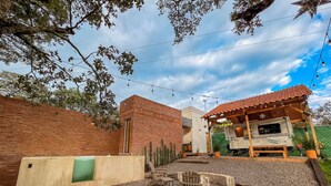 A rustic outdoor area with a gravel patio, a wooden bench, a small table, and a covered seating area with a red-tiled roof. - Glamping with Jacuzzi in Guanajuato (pet friendly) (Guanajuato)