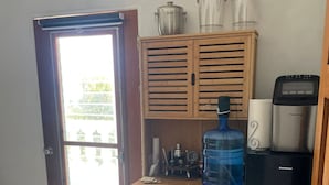 Une cuisine compacte équipée d’un réfrigérateur intégré, d’un distributeur d’eau et d’une machine à café.