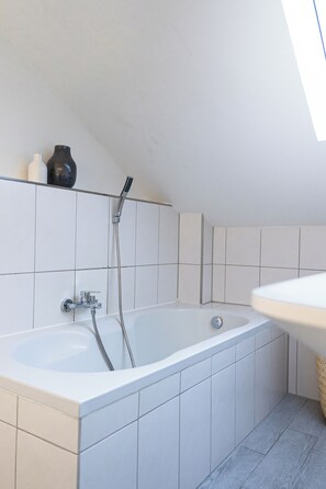 Une salle de bain moderne avec une baignoire sur pieds, une douche et un lavabo blanc.