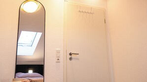 A bedroom with a skylight, a bed with a patterned blanket, a white door, and a mirror reflecting the room. - Alpine Lodge am Alpsee - Ski proximity & mountain view DG (Immenstadt im Allgäu)