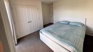 Un dormitorio con cama, armario y puerta.