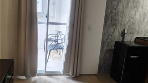 A room with a sliding glass door leading to a balcony with a table and chairs. - Apartment in the Rio Wonder Condominium - Downtown Rio de Janeiro. Close to EVERYTHING. (Rio de Janeiro)