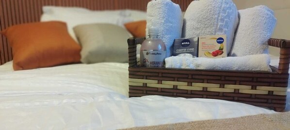 A hotel room with a neatly made bed, a small wooden side table with toiletries, and a brick-patterned headboard. - Apartment in the Rio Wonder Condominium - Downtown Rio de Janeiro. Close to EVERYTHING. (Rio de Janeiro)