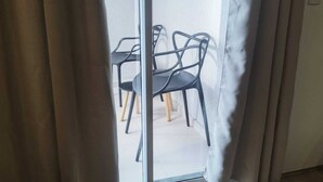 A view through a window with a curtain, revealing a dining area with a table and chairs. - Apartment in the Rio Wonder Condominium - Downtown Rio de Janeiro. Close to EVERYTHING. (Rio de Janeiro)
