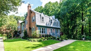 A two-story house with a brick facade, blue trim, and a front yard with a sidewalk. - Wooded 3BR Retreat Near DC: Free Parking. Pet/Infant/Kids-Friendly. Private Deck (Silver Spring)