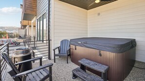 An outdoor patio with a hot tub, seating, and a view of the street. - Risen Ranch by Crafty Casitas Hospitality (Mountain Green)