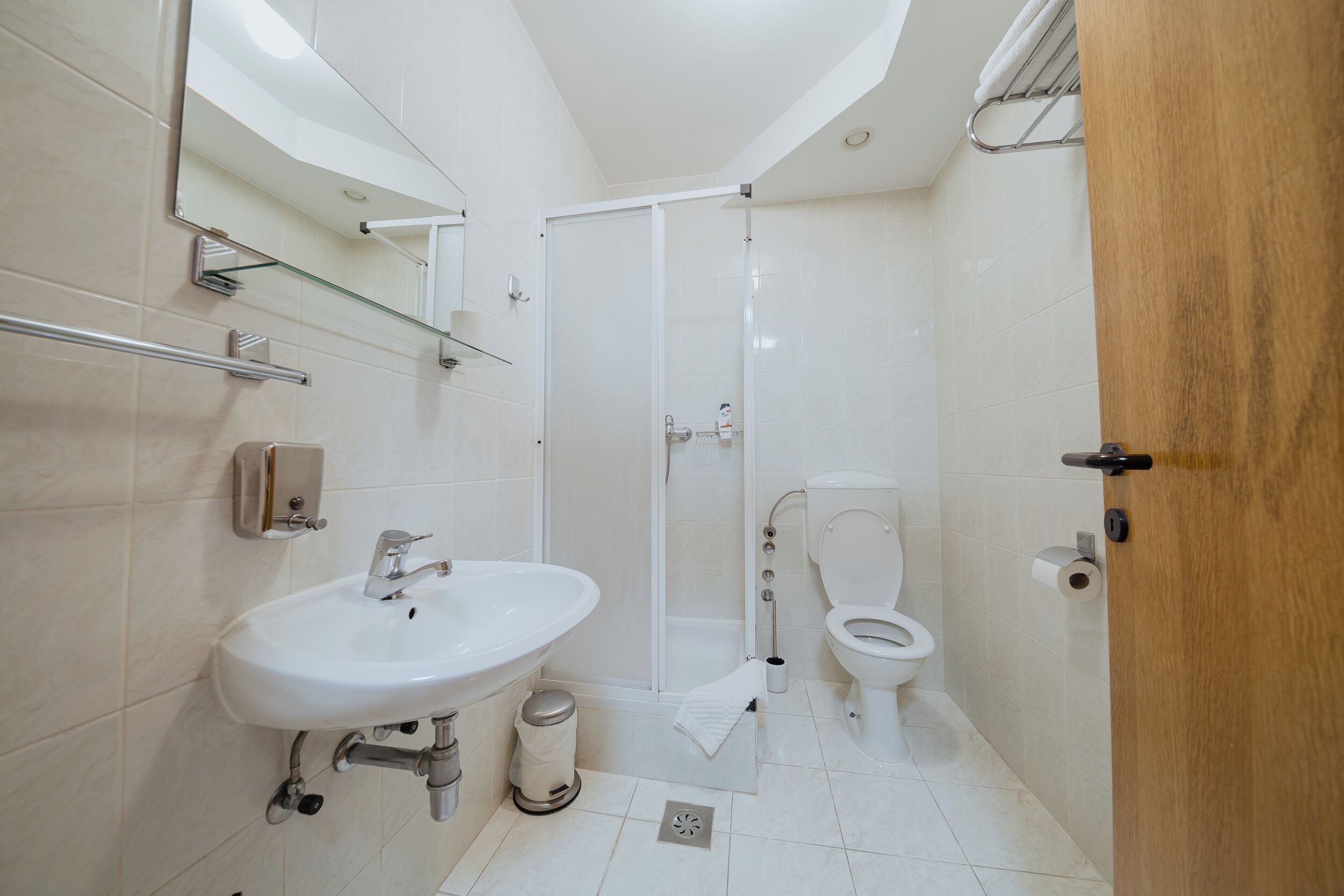 A modern bathroom with a white sink, toilet, and shower.