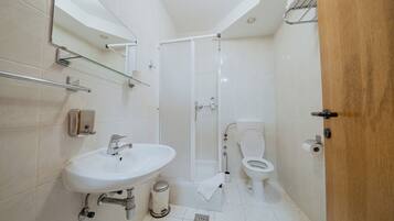 A modern bathroom with a white sink, toilet, and shower.