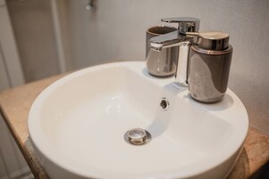 Un lavamanos con grifo cromado y dispensador de jabón.