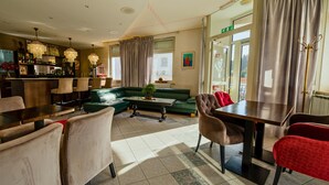 A hotel lobby with a green sofa, a dining table, and chairs.