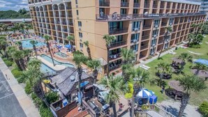 A multi-story hotel with a pool area, palm trees, and outdoor seating. - Charming studio in soothing Myrtle Beach with fitness room, multiple pools (Myrtle Beach)